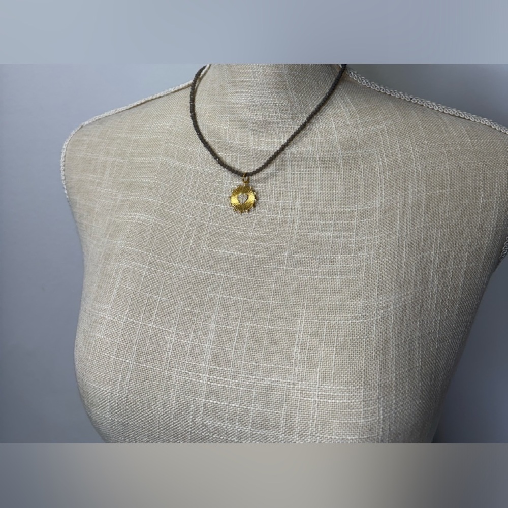 Gray beaded necklace with gold circle heart charm.